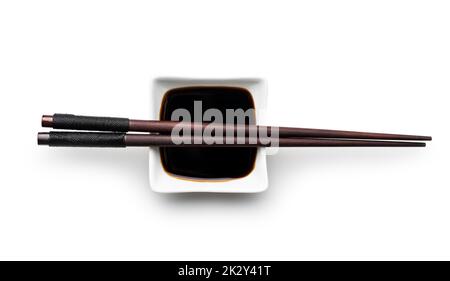 Soy sauce in bowl and chopsticks isolated on white background. Stock Photo