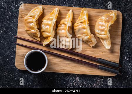 Chinese dumplings abd soy sauce on cutting board. Stock Photo