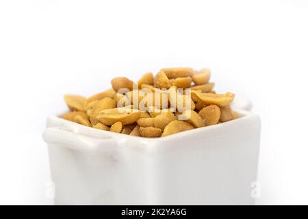 Panorama of roasted salted peanuts in a white square bowl.  Isolated against a white background. Stock Photo