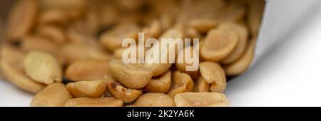 Panorama of open packet of peanuts showing peanuts inside.  Isolated against white background Stock Photo