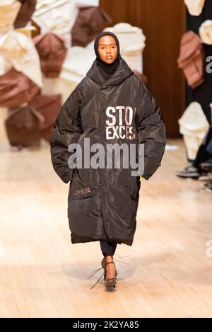 Model, modelling on catwalk for VIN+OMI 'Opinions' show for London Fashion Week 2022. Recycled materials. Sustainable fashion. Puffer coat with slogan Stock Photo