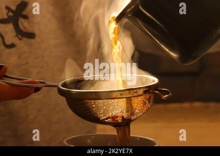 Pouring tea in a cup with a strainer Stock Photo