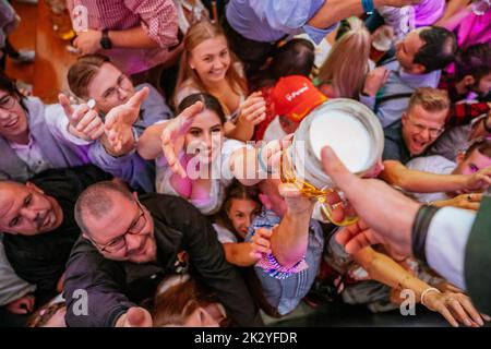 Stuttgart, Germany. 23rd Sep, 2022. Visitors look forward to the first free beer on the opening day of the Cannstatter Volksfest on the Wasen in Stuttgart. The 'Wasen' is the second largest folk festival in Germany after the Munich Oktoberfest. Credit: Thomas Niedermüller/dpa/Alamy Live News Stock Photo