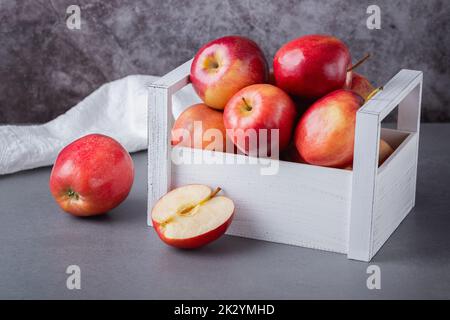 Fresh red apples in a wooden box on a grey background. Organic food Stock Photo