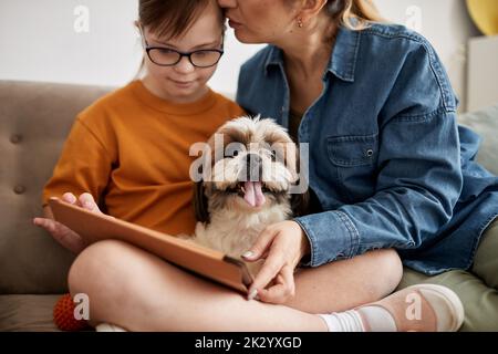 Portrait of small cute dog sitting on couch with family and looking at camera, copy space Stock Photo