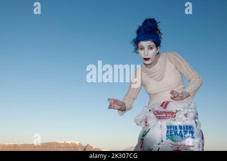 A funny woman mimes against the blue sky during a performance on the island of Santorini in Greece Stock Photo