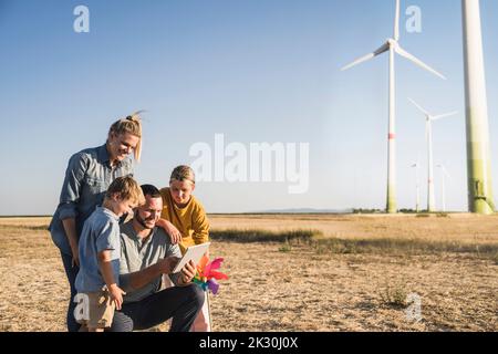 Smiling family using digital tablet in wind park Stock Photo