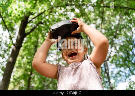 Happy girl with VR glasses standing in front of trees at park Stock Photo