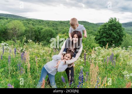 Mother with daughter and son in lupine flowers meadow Stock Photo