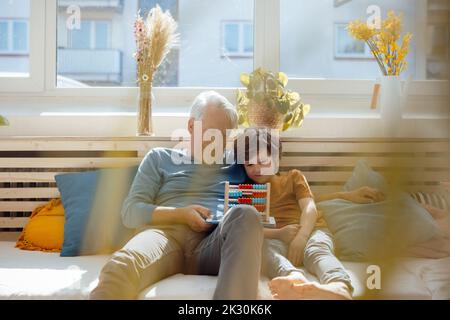 Grandfather teaching abacus to grandson at home Stock Photo