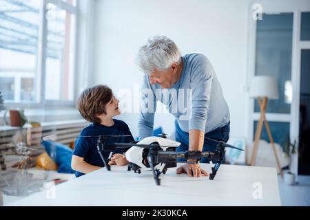 Grandfather and grandson talking with drone on table in living room Stock Photo