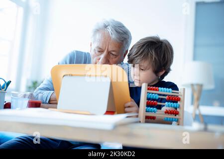 Senior man and boy using tablet PC at home Stock Photo