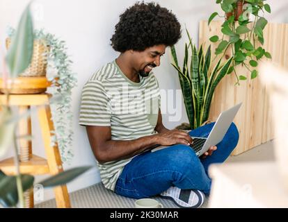 Happy African man using laptop at home Stock Photo