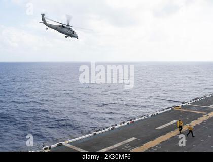 220921-N-TT639-2083 PHILIPPINE SEA (Sept. 21, 2022) – An MH-60S Sea Hawk helicopter assigned to Helicopter Sea Combat Squadron (HSC) 23 flies by amphibious assault carrier USS Tripoli (LHA 7) Sept. 21, 2022. Tripoli is operating in the U.S. 7th Fleet area of operations to enhance interoperability with allies and partners and serve as a ready response force to defend peace and maintain stability in the Indo-Pacific region.  (U.S. Navy photo by Mass Communication Specialist 3rd Class Christopher Sypert) Stock Photo