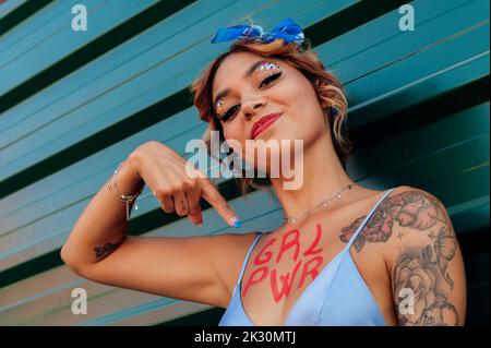 Young woman pointing girl power text on chest Stock Photo