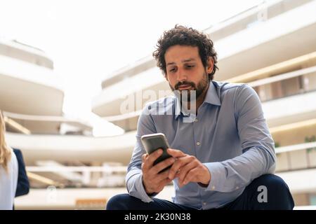 Businessman text messaging through mobile phone in office Stock Photo