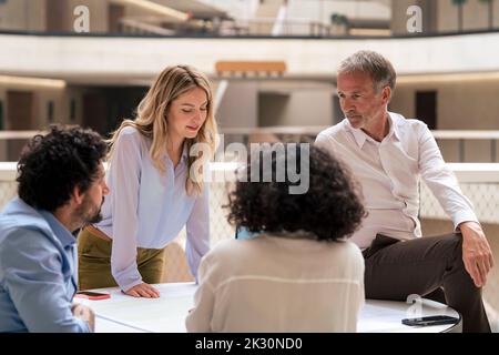 Multiracial business colleagues discussing strategy over document in meeting Stock Photo