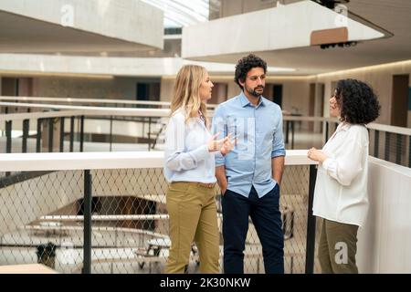 Multiracial business colleagues discussing ideas in corridor Stock Photo