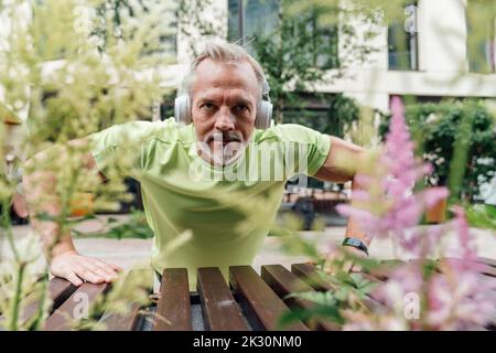 Man wearing headphones doing push-ups Stock Photo