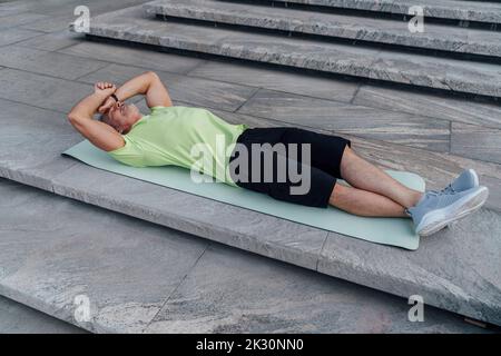 Tired man lying on yoga mat near steps Stock Photo