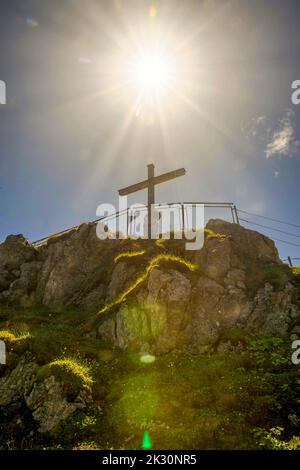 Germany, Bavaria, Sun shining over summit cross on Nebelhorn mountain Stock Photo