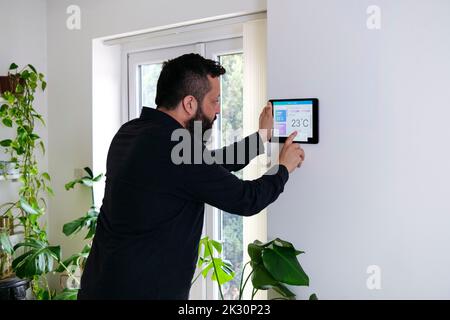 Mature man controlling temperature through tablet PC at home Stock Photo