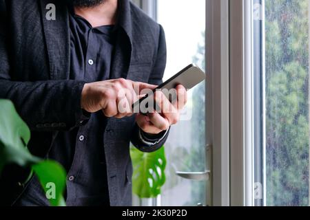 Businessman using smart phone by window at home Stock Photo