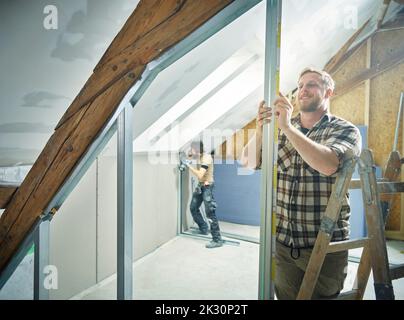Smiling construction worker installing metal for drywall Stock Photo