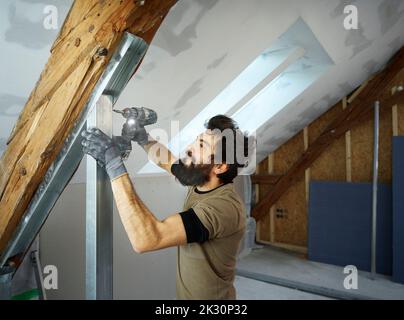 Construction worker using drill on metal at site Stock Photo