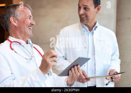Happy doctors discussing over tablet PC in hospital Stock Photo