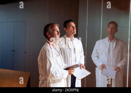 Thoughtful doctors with report and tablet PC in hospital Stock Photo