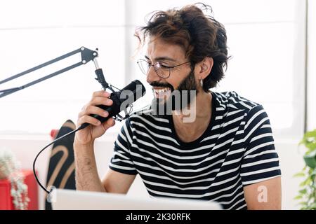Happy man with microphone recording podcast at home studio Stock Photo
