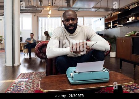 Confident businessman sitting in armchair using typewriter Stock Photo