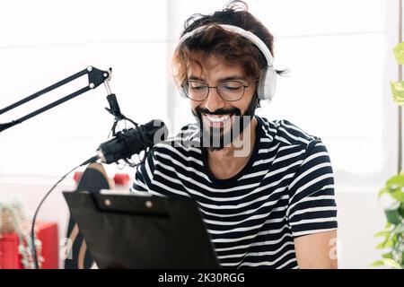 Happy man reading script and recording through microphone at home studio Stock Photo