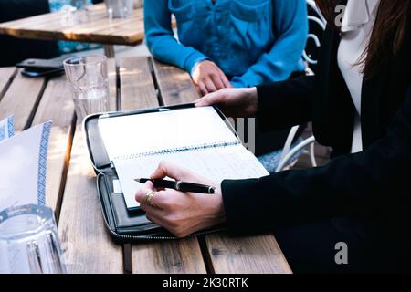 Businesswoman with colleague making notes in diary at restaurant Stock Photo