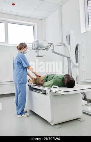 Nurse wearing scrubs taking X-ray shot of patient in clinic Stock Photo