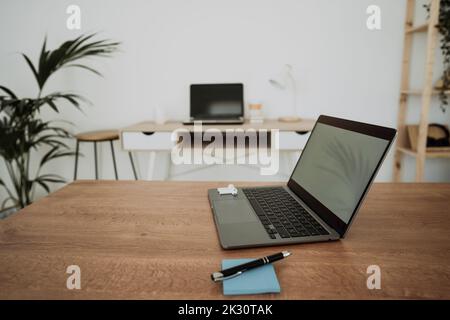 Laptop by adhesive note and pen on table in office Stock Photo