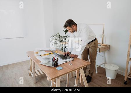 Architect using laptop at desk in office Stock Photo