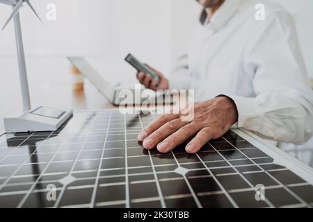 Hands of engineer analyzing solar panel at desk in office Stock Photo