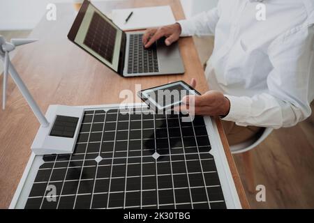 Engineer using laptop sitting with green technology at desk in office Stock Photo