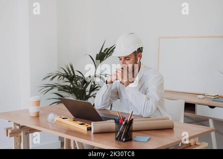 Thoughtful engineer with laptop at desk in office Stock Photo
