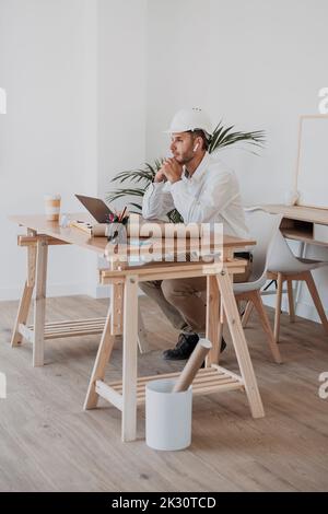 Thoughtful engineer with laptop at desk in office Stock Photo