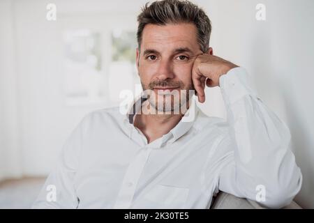 Smiling businessman on sofa in office Stock Photo