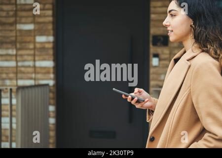 Thoughtful woman with mobile phone by building Stock Photo