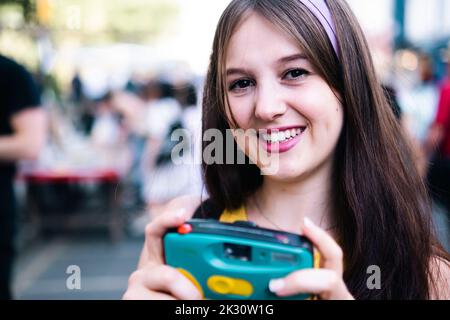 Happy woman with long hair holding camera Stock Photo