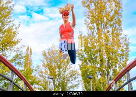 Smiling young athlete jumping on footbridge Stock Photo