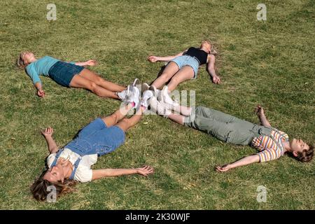 Friends lying together on grass at park Stock Photo
