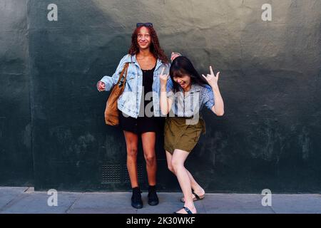 Happy friends having fun together standing in front of wall Stock Photo