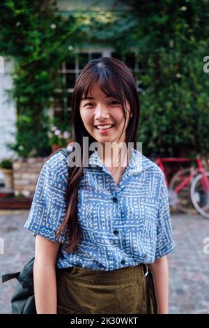 Happy young woman standing on footpath Stock Photo