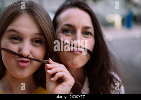 Two women having fun making mustache with hair Stock Photo